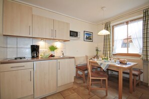 A kitchen with wooden cabinets, a microwave, and a dining table set for breakfast.