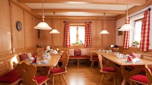 A wooden dining area with red upholstered chairs and benches, wooden tables, and pendant lights. - (07) Zwei-Raum-Ferienwohnung (Reit im Winkl)