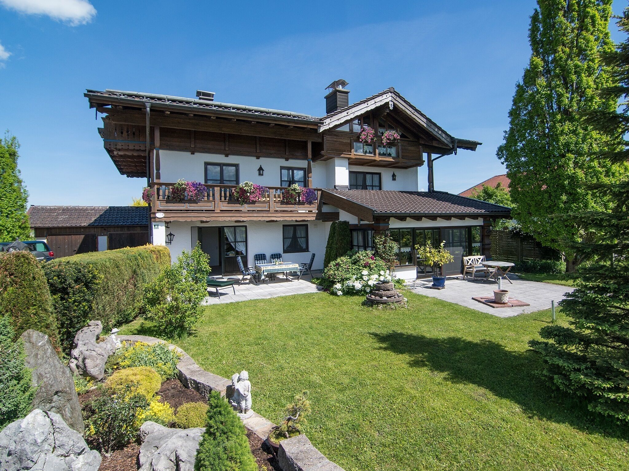 En toetagers chalet med balkon, udendørs møbler og en velplejet have.