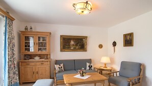 Una sala de estar acogedora con un aparador de madera, un sofá, una mesa de centro y una lámpara.
