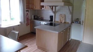 A compact kitchen with wooden cabinets, a built-in stove, and a small countertop. - Ferienwohnung 65 qm, für 2-4 Personen, 2 getrennte Schlafzimmer, Balkon u. Nichtraucher (Schönau am Königssee)