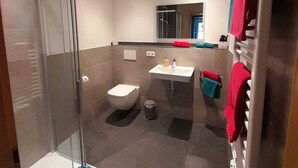 A modern bathroom with a glass shower enclosure, a toilet, a sink, and a mirror. - Three-room vacation apartment 52sqm time-out, 2 extra bedrooms, kitchen, balcony (Reit im Winkl)