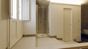 Una habitación con ducha, una cama y una puerta que da a otra estancia.