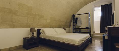 A bedroom with a bed, nightstand, lamp, and a wardrobe.