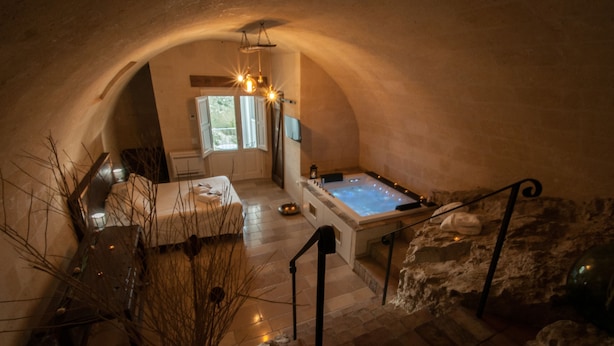 Una habitación en arco con bañera de hidromasaje, una cama y una ventana.