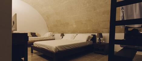 Un dormitorio con dos camas, una mesita de noche de madera, una lámpara y un sillón colgante.