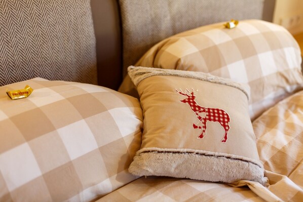 A bed with checkered bedding and a pillow with a deer design.
