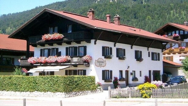 Un bâtiment de style alpin traditionnel, doté de nombreuses fenêtres et de balcons ornés de fleurs.