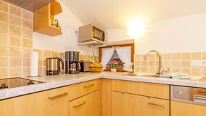 Une cuisine avec des meubles de rangement en bois, un four à micro-ondes, une machine à café et un évier.