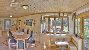 Ein gemütliches Holzinterieur mit einem runden Esstisch, Stühlen und einer Bank.