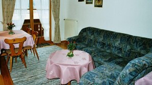 Une pièce chaleureuse avec une table à manger en bois, des chaises, un canapé et un radiateur.