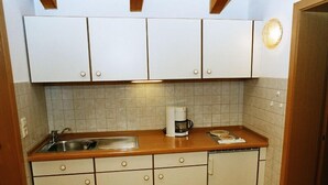 Une cuisine de taille réduite avec des meubles blancs, une machine à café et un évier.