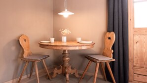 Una mesa redonda de madera con cuatro sillas, una lámpara colgante y un jarrón con flores.