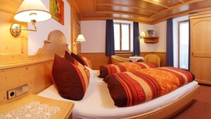 Tunnelmallinen huone, jossa on suuri sänky, kaksi yöpöytävalaisinta, pieni pöytä ja tuoli.