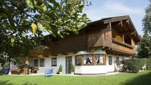 A two-story wooden house with a balcony, surrounded by a well-maintained lawn and trees. - 5. Fewo Hochgern, 37 qm, 1- 3 Pers., 1 Schlafzimmer, 1 Wohnschlafraum, Süd-Balkon (Grassau)