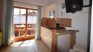 A compact kitchen with a wooden countertop, a built-in oven, and a television mounted on the wall. - 5. Fewo Hochgern, 37 qm, 1- 3 Pers., 1 Schlafzimmer, 1 Wohnschlafraum, Süd-Balkon (Grassau)