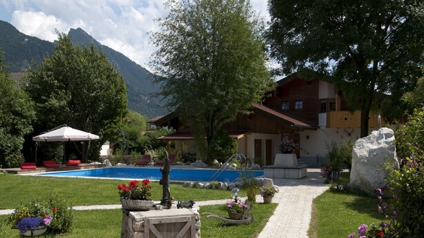 A pool area with a stone pathway leading to a wooden cabin. - 5. Fewo Hochgern, 37 qm, 1- 3 Pers., 1 Schlafzimmer, 1 Wohnschlafraum, Süd-Balkon (Grassau)