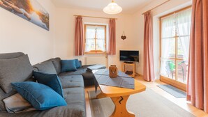 A modern living room with a sofa, a coffee table, and a TV. - Ferienwohnung III° extra Schlafzimmer, Süd-Balkon, 65 qm° (Aschau im Chiemgau)