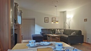 Ein Essbereich mit einem Tisch für vier Personen, einer Couch und einer Lampe.