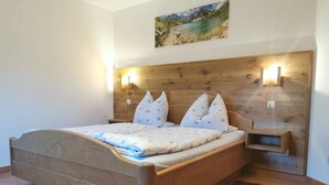 Ein Schlafzimmer mit einem hölzernen Bett, einem Nachttisch, einer Wandlampe und einem Gemälde über dem Bett.
