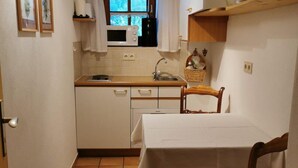 A compact kitchen with a microwave, sink, and a dining area with a table and chair. - Dürrach vacation apartment with covered balcony (Reit im Winkl)
