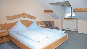 Un dormitorio con una cama de madera, una mesita de noche, una silla y una ventana con cortinas.