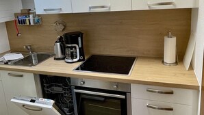 A compact kitchen with a built-in dishwasher, oven, and a coffee maker on the countertop.