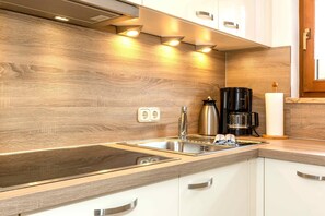 A modern kitchen with a wooden backsplash, stainless steel sink, and white cabinets.
