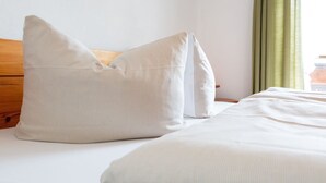 Un lit bien fait, avec une literie blanche et deux grands oreillers.
