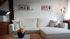 A living room with a sofa, a coffee table, a lamp, and framed artwork on the wall. - Ferienwohnung Teddy, 68 m² (Siegsdorf)