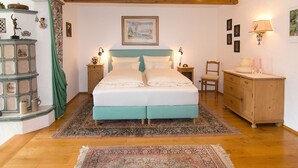 A bedroom with a bed, nightstands, a dresser, and a window with curtains. - Ferienwohnung 1, 65 qm, f. 1-2 Personen (Grassau)