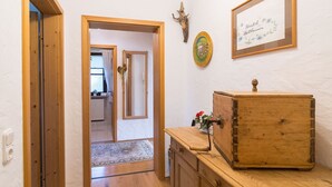 A hallway with wooden flooring, a wooden cabinet with a vintage design, a framed picture on the wall, and a door leading to another room. - Ferienwohnung 1, 65 qm, f. 1-2 Personen (Grassau)