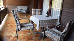 Un patio techado con sillas de mimbre, una mesa con mantel estampado de estrellas y un banco.