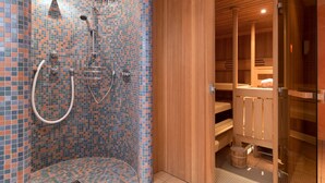A modern spa with a mosaic-tiled shower area and wooden sauna compartments.