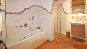 Een badkamer met een badkuip, douche en wastafel.
