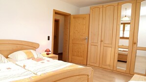 A bedroom with a wooden bed, a nightstand, a wardrobe, and a mirror. - holiday flat (Truchtlaching)
