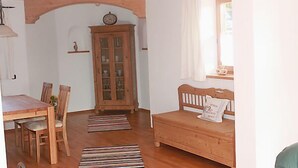 A cozy room with a wooden dining table, chairs, a cabinet, and a bed with a pillow. - holiday flat (Truchtlaching)