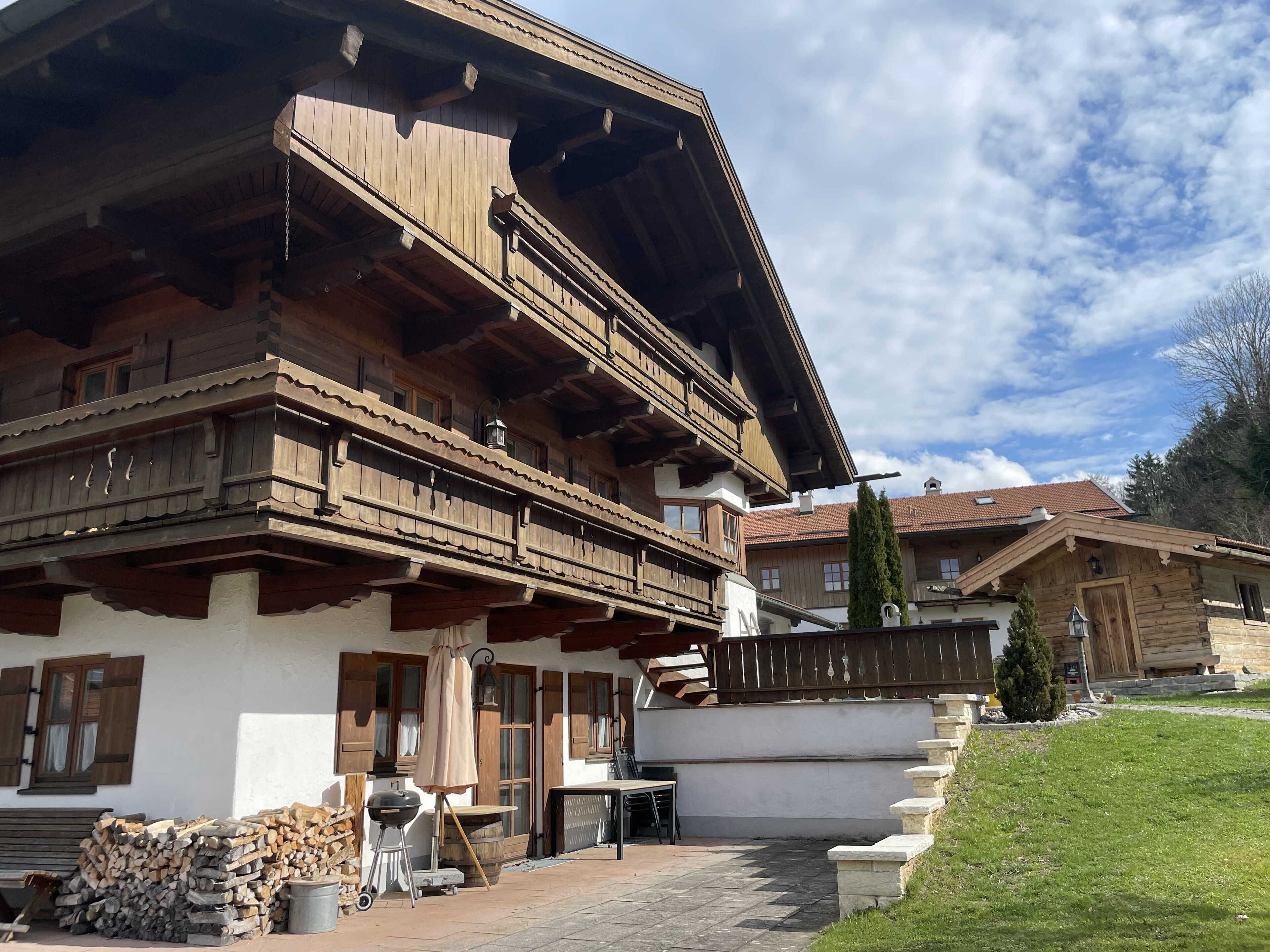 Ein traditionelles Holzchalet mit Balkon, Grillmöglichkeit und einem Kiesweg, der zum Eingang führt.