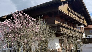 A traditional wooden chalet with a balcony and a view of a flowering tree. - holiday flat (Truchtlaching)