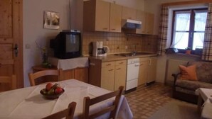 Una cocina compacta con armarios de madera, una cafetera y un televisor.