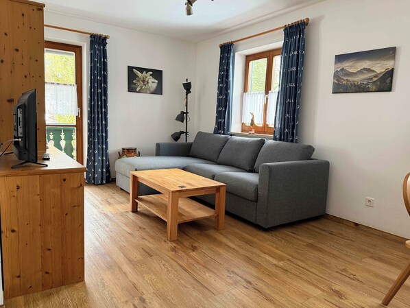 Un salon avec un canapé, une table basse en bois, un téléviseur et une lampe.