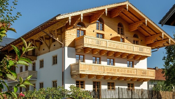 A traditional Alpine-style building with a wooden balcony, a sign indicating it is a 'Winnmahof' in Bavaria, and a stone wall in the foreground. - Ferienwohnung "Chiemsee", 110 qm Erdgeschoss, 3 separate Schlafzimmer (Höslwang)