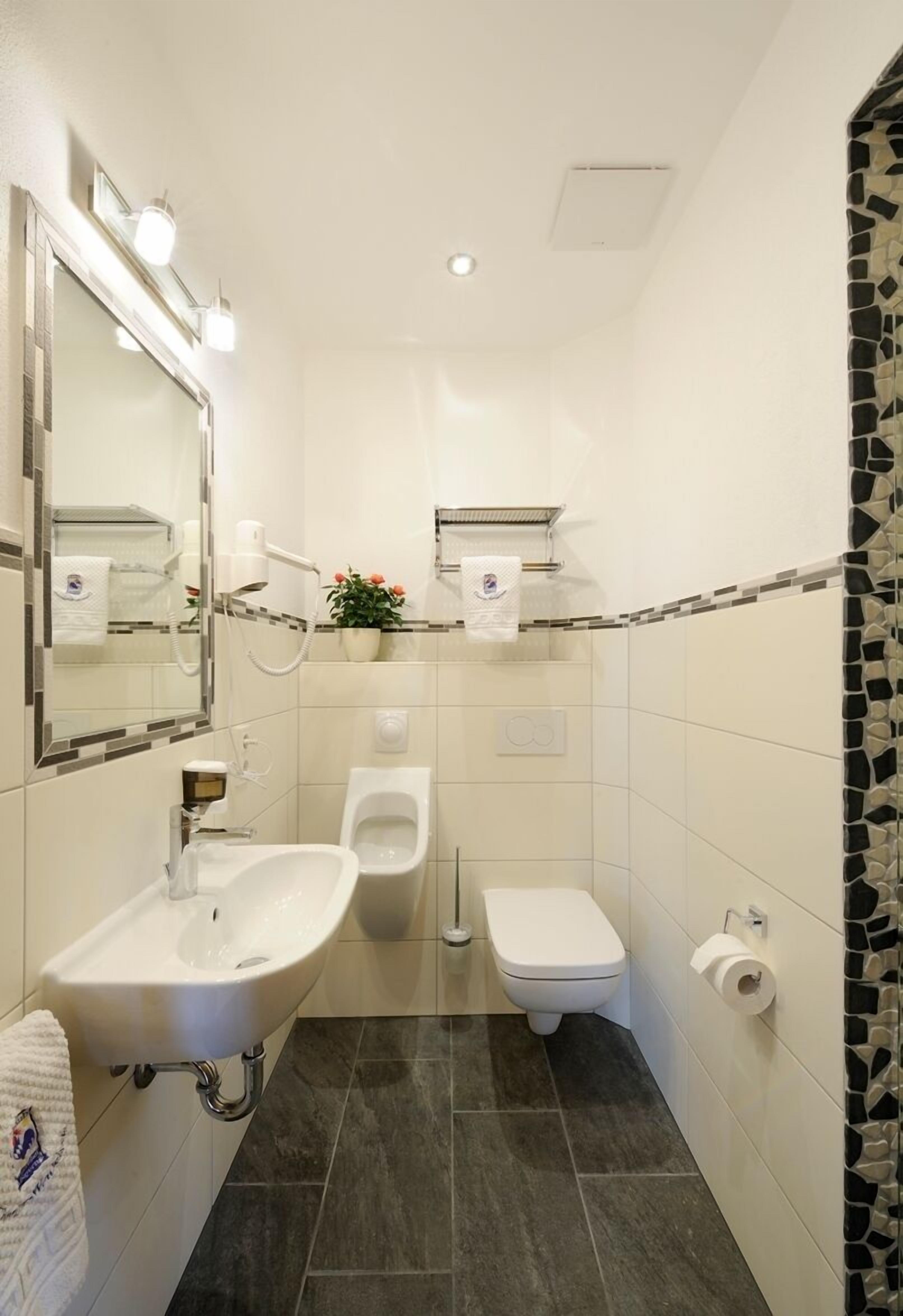 Un baño pequeño con lavamanos, bidé, inodoro y espejo con iluminación.