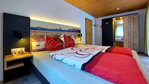 Un dormitorio con una cama, una mesita de noche, una lámpara de pared, un cuadro y un techo de madera.