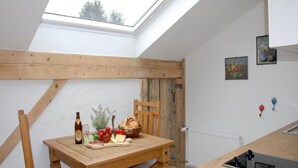 A small kitchen with a wooden table set for a meal, a window above the table, and a radiator on the wall.