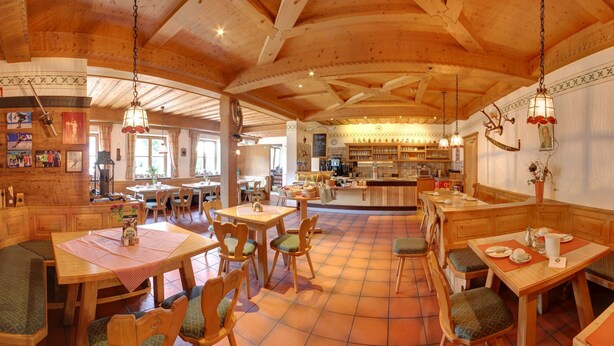Um restaurante acolhedor com mobiliário de madeira, piso de azulejos e um espaço de bar.