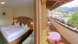 Quarto de hotel com cama, mesa de cabeceira e vista para a cidade e montanhas.