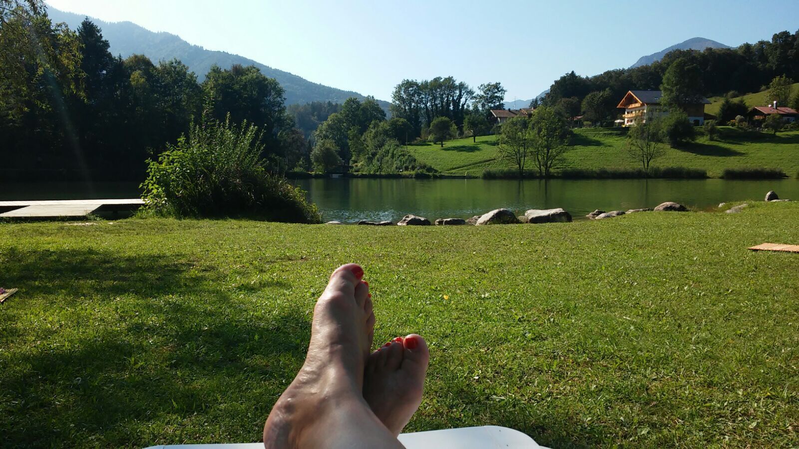 Een grasrijk gebied met een meer en bergen op de achtergrond.