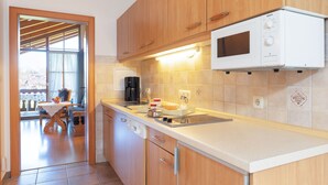 A modern kitchen with wooden cabinets, a Bosch microwave, and a dining area with a table and chairs. - Three-room vacation apartment 65sqm, shower/WC, 2 extra bedrooms, kitchen, balcony (Reit im Winkl)