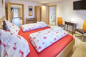 A hotel room with a large bed, a desk, a chair, and a TV mounted on the wall. - Apartment Oberstadel 52 sqm for 1-4 persons barrier-free (Altötting)